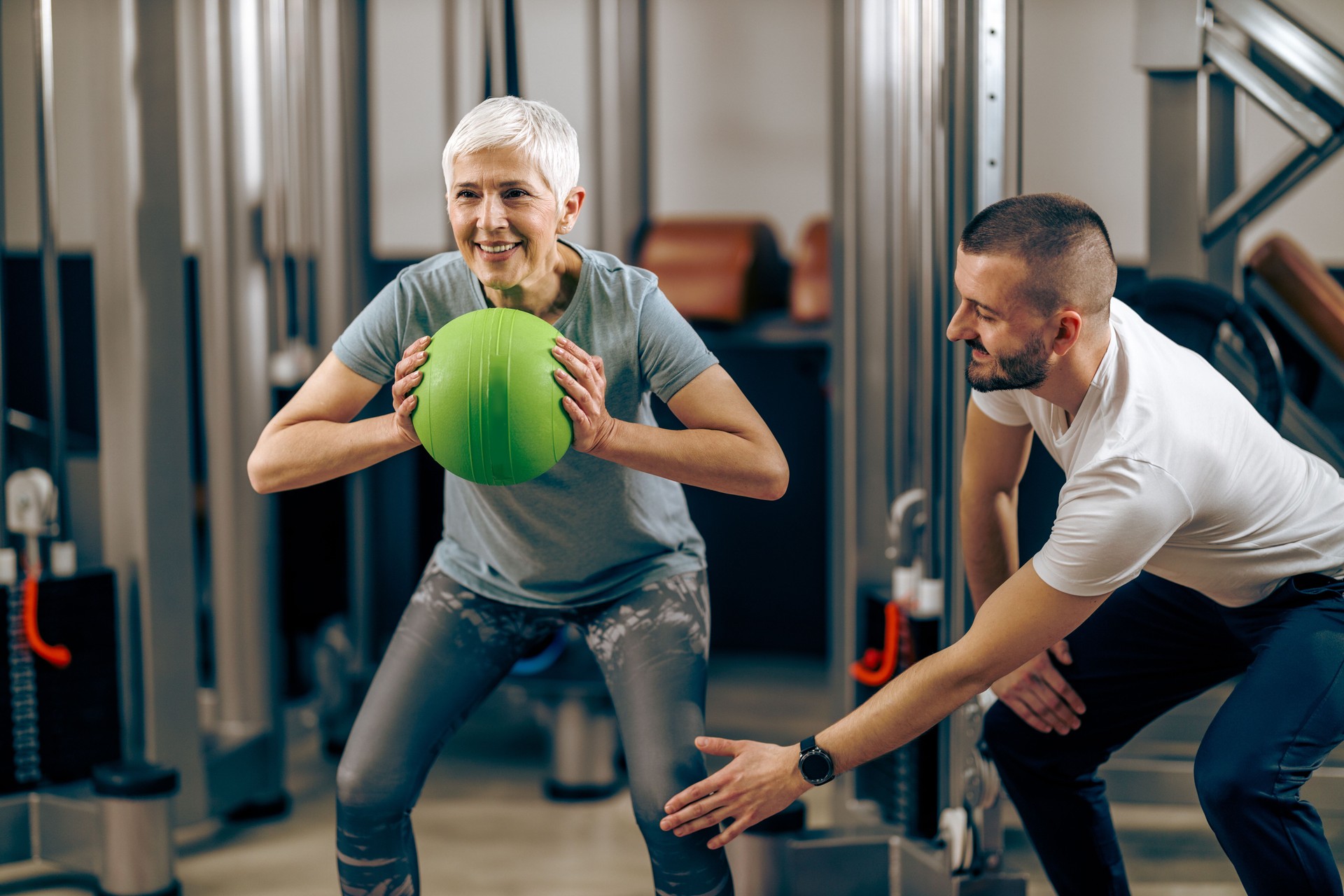 Senior Woman Doing Workout With Coach In The Gym